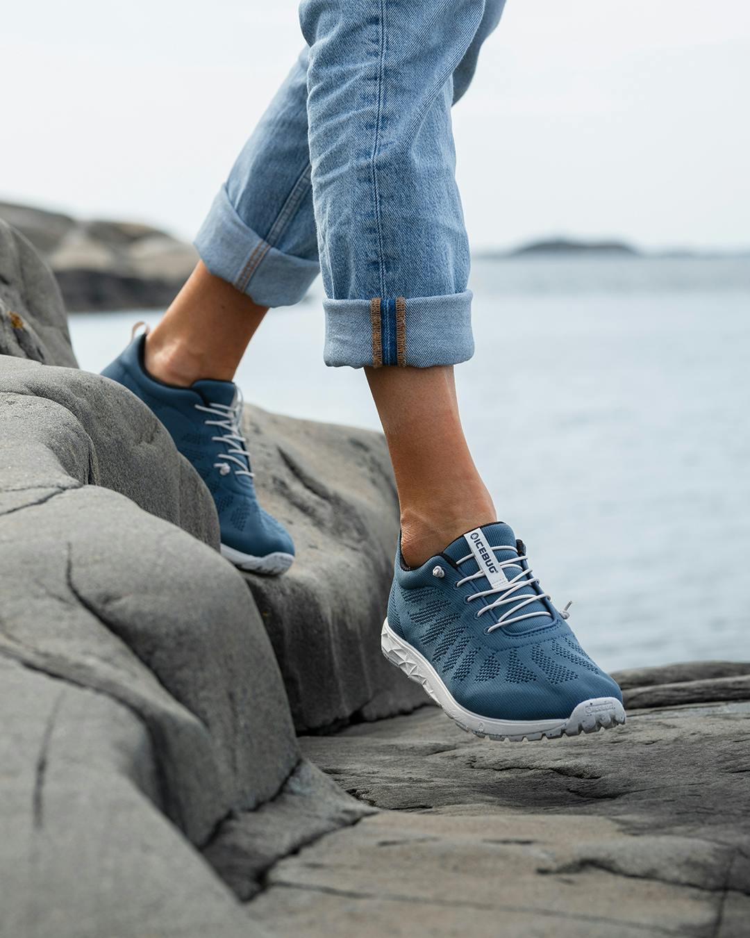 a person in blue Icebug sneakers walking in the cliffs