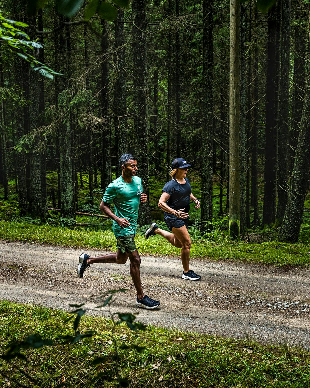 a man and a woman running on a trail in the woods wearing Icebug running shoes