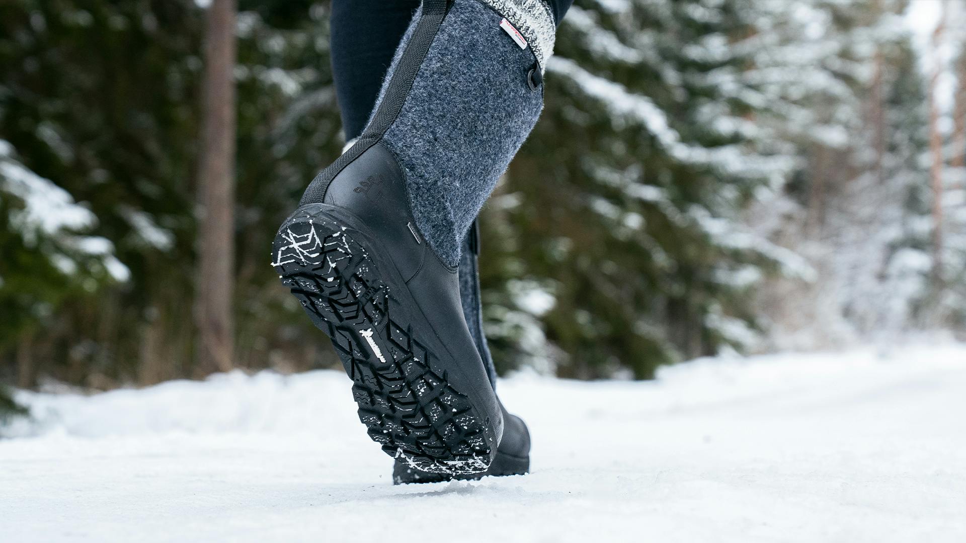 A person walking on a snowy road with a pair of Icebug shoes