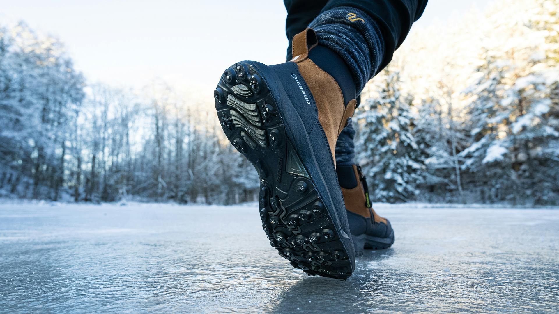 person walking on ice with a pair of brown studded icebug winter boots