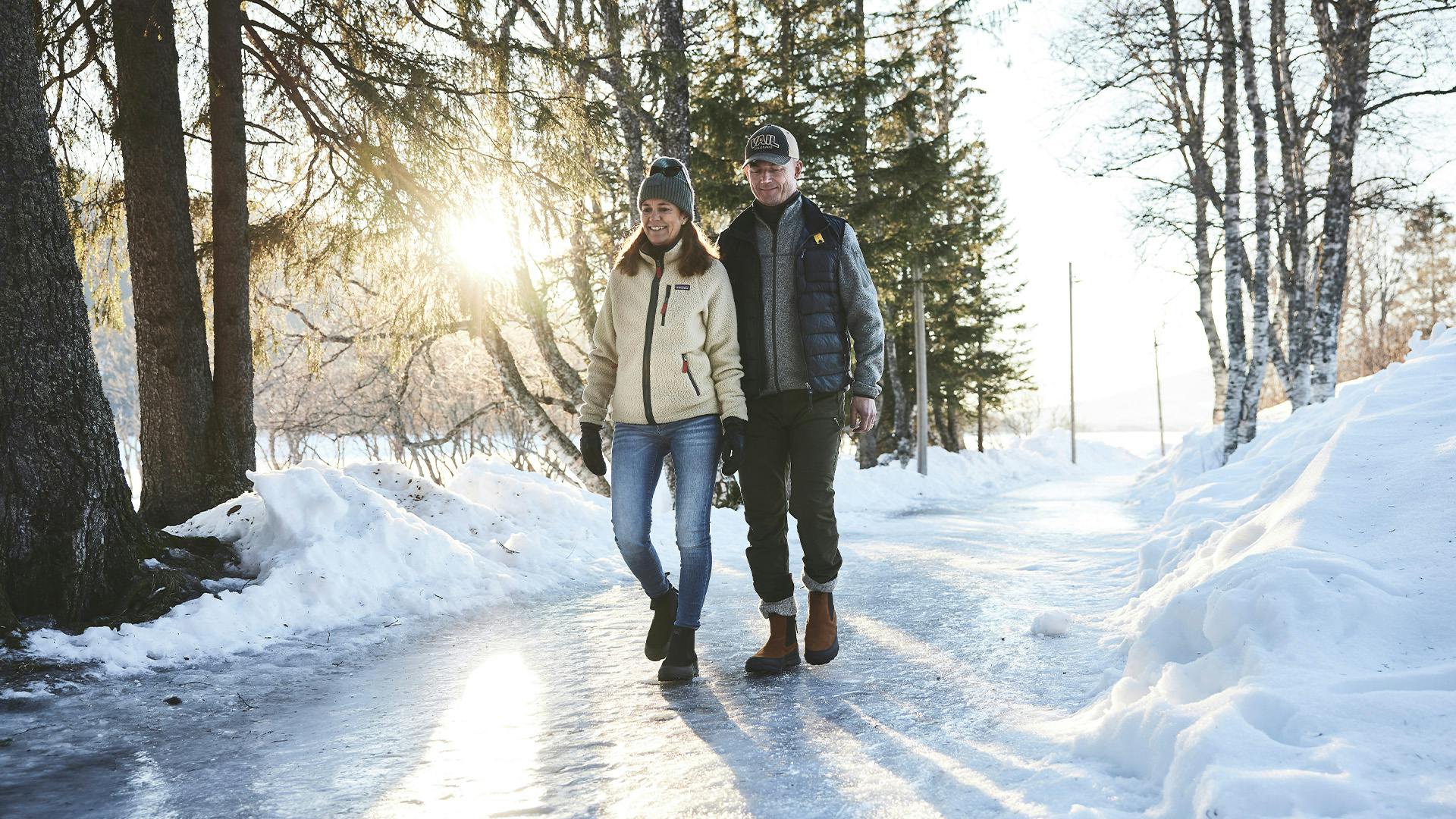 A couple walking on an icy road, enjoying a winter walk together.