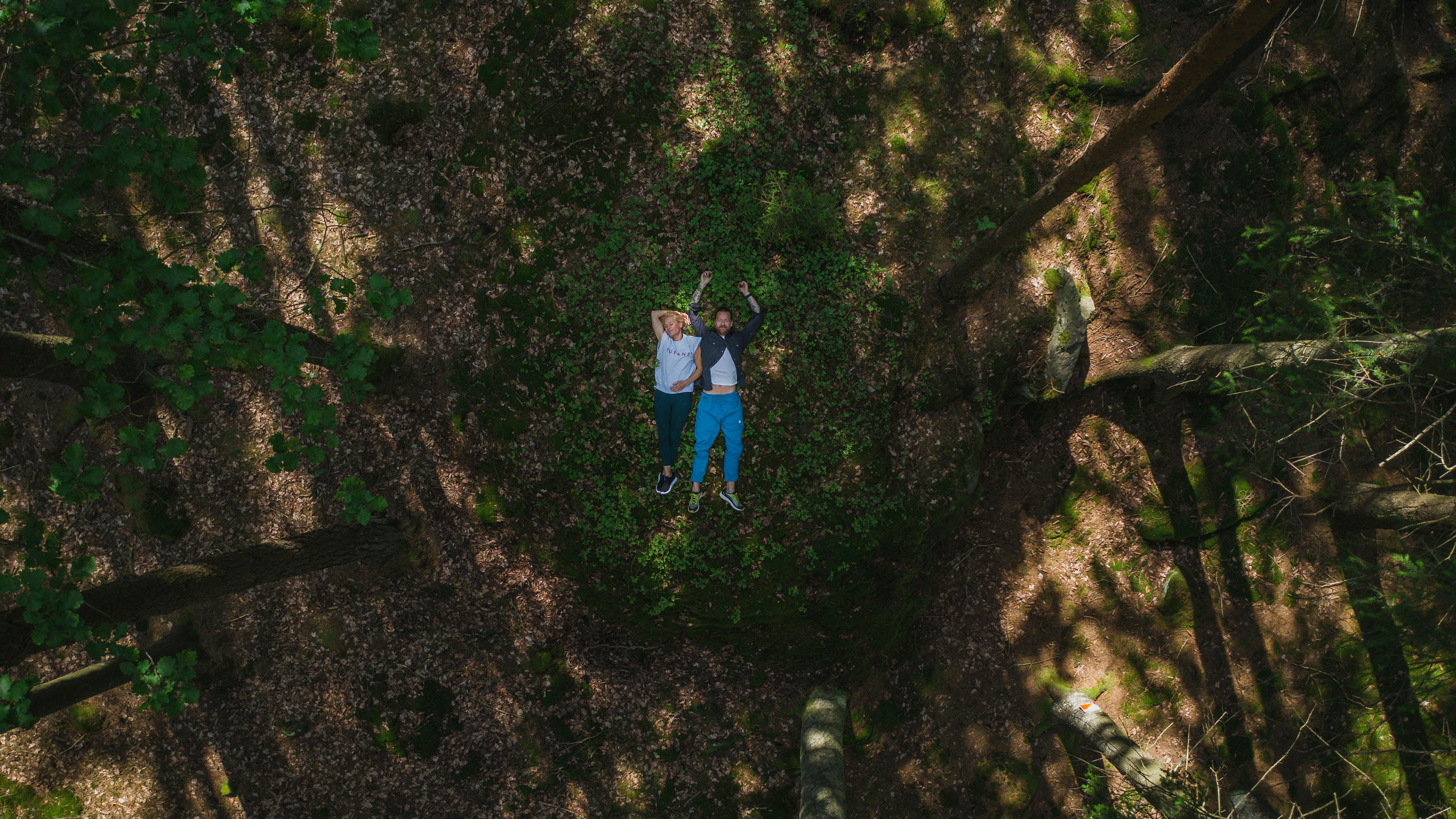 a couple laying on the ground in the woods
